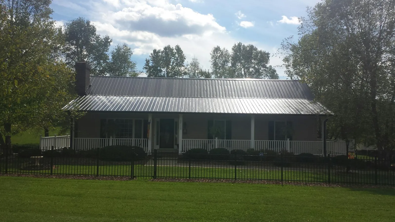 Gray metal roof on a brick ranch with a full width front porch — Gutter Guard Installation work by our crew in Yountville
