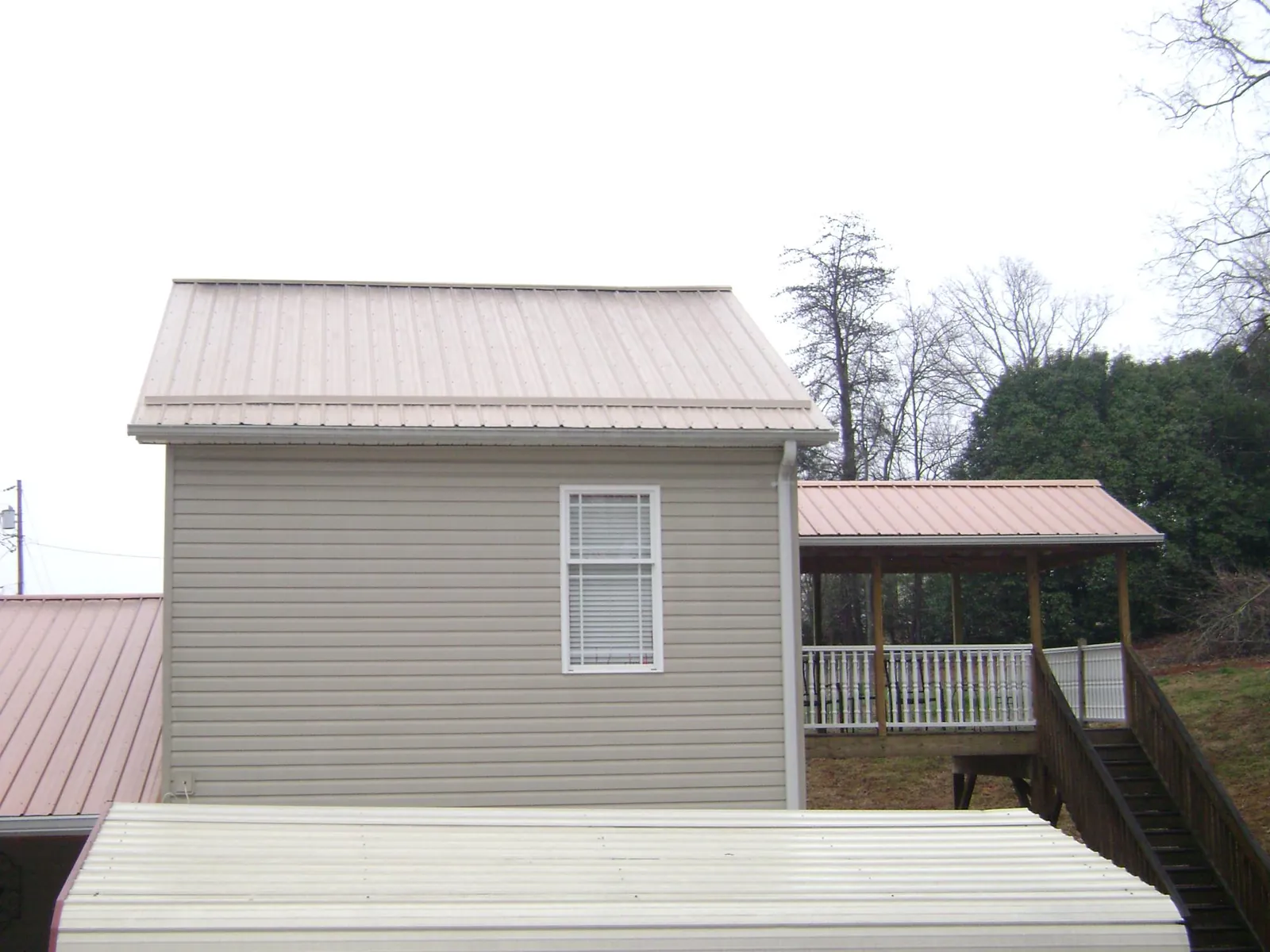 Tan metal roofs on a two story addition and attached porch, from a Roof Replacement job in Yountville